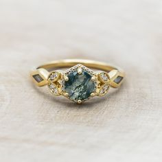 a close up of a ring with a stone in the middle and diamonds around it