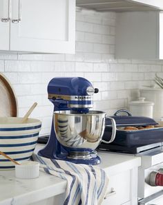 a blue kitchen mixer sitting on top of a counter next to bowls and utensils