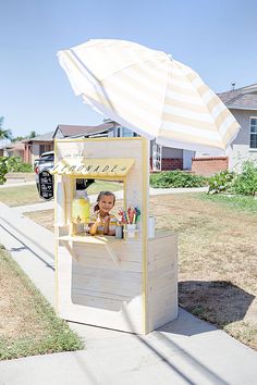 a little boy sitting at a food stand under an umbrella