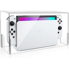 a white nintendo wii console sitting on top of a glass shelf with two controllers in front of it