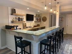 a kitchen with an island and lots of stools in front of the bar area