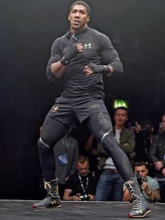 a man standing on top of a stage in front of a crowd wearing black clothing