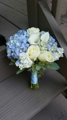 a blue and white bouquet sitting on top of a wooden bench