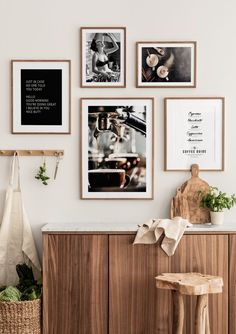 several framed pictures hang on the wall above a wooden cabinet with a stool and potted plant