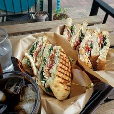 two sandwiches with toothpicks are sitting on the table next to some sodas