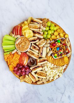 a platter filled with snacks, crackers and fruit