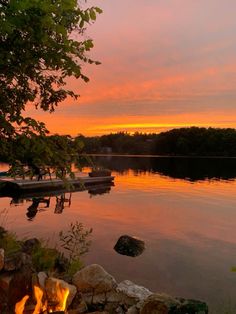 there is a fire pit in the middle of the water with boats on it at sunset