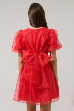 If you like to be trendy, you need Borza Organza Mini Dress! It’s such an adorable dress that has angled, ruffled short sleeves. The back side has an invisible zipper closure followed by a big bow tie back detail. Bodice has a relaxed fit and has a flowy skirt with an organza fabric all over this dress. It will look cuter with heels and your favorite jewelry pieces. - Lined- Puffed short sleeves- Bow details- Zipper back- Comes in 2 colorsSize + Fit - Model is 5'10" and wearing size XS- Measurem Party Puff Sleeve Dress With Tie Back, Puff Sleeve Mini Dress With Bow For Party, Mini Dress With Tie Back And Short Sleeves, Short Sleeve Summer Dress With Bow Tie Back, Evening Dresses With Tie Back And Short Sleeves, Fitted Mini Dress With Bow And Short Sleeves, Puff Sleeve Dress With Bow For Party, Ruffled Short Sleeve Mini Dress For Party, Ruffled Mini Dress With Short Sleeves For Party