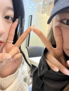 two young women making the v sign with their hands and wearing rings on their fingers