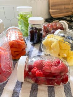 jars filled with fruit and vegetables sitting on top of a table