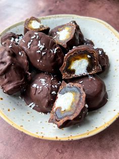 a plate full of chocolate covered donuts with white sprinkles on them