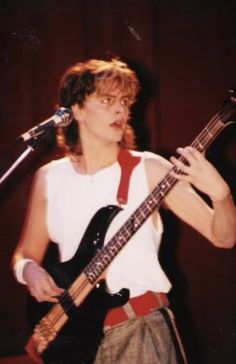 a man holding a guitar while standing in front of a microphone