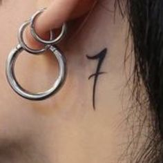 a close up of a person's ear with a cross and number tattoo on it