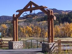 a wooden structure with a sign hanging from it's side in front of mountains