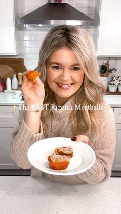 a woman holding a plate with food on it in her hands and smiling at the camera