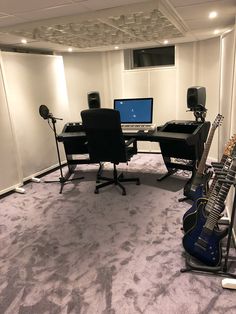 a room with guitars, laptops and other musical equipment