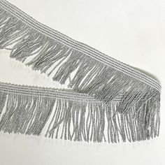 two silver fringes are on a white surface