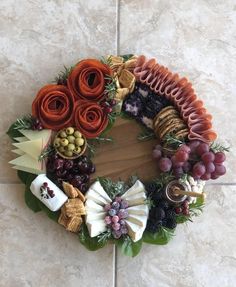 a wreath made out of fruits, vegetables and meats on a tile floor in front of a wall