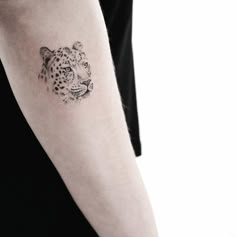 a black and white photo of a leopard tattoo on the arm