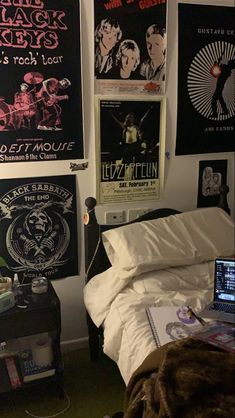 a bedroom with posters on the wall and a bed in front of a laptop computer