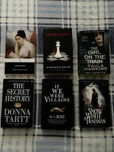 four books are laying on a plaid blanket, one is black and the other is white