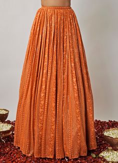 Step into elegance with the Orange Embroidered Kalidar Lehenga Set, a perfect blend of traditional charm and modern style. Crafted from lightweight georgette fabric, the flowy kalidar orange lehenga is adorned with shimmering sequins and intricate threadwork, offering a rich, luxurious feel. Lehenga includes pockets. Paired with a sleeveless blouse enhances the look with delicate mirror work, zari, and pearl embroidery, adding a radiant touch. Completed with a matching georgette dupatta, featuring a scalloped, sequin-embellished border and subtle buttis. Ideal Lehenga for Mehndi, Sangeet ceremonies, or wedding guest attire, this outfit radiates timeless grace. Composition : Blouse, Lehenga and Dupatta - Viscose Georgette Care: Dry Clean Only and Vacuum Storage This product can be customize