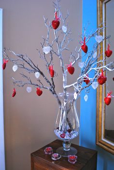 a vase filled with red apples sitting on top of a table next to a mirror