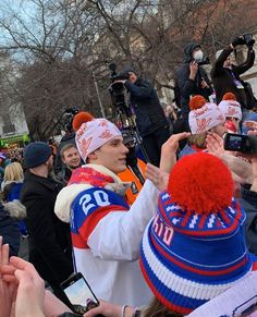 a group of people standing around each other in front of a crowd with cell phones