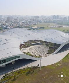 an aerial view of a large building in the middle of a city with lots of grass