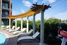 a row of lounge chairs sitting next to a swimming pool in front of an apartment building