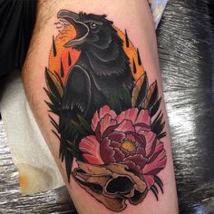 a black bird sitting on top of a skull with flowers in it's beak