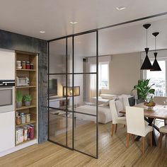 an open concept kitchen and living room with wood flooring, white furniture and black pendant lights