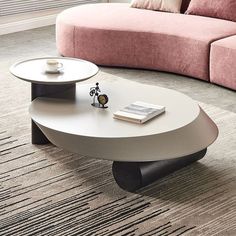 a coffee table with a book on it in front of a pink couch and rug