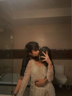 a woman taking a selfie in front of a bathroom mirror