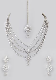 Featuring a layered faux diamond necklace with a white finish enhanced with tiered diamond pendants. Perfectly matched with earrings and a delicate mang tikka. Perfect for for modern bride for wedding and festive occasions. Composition : Mixed Metal Care: Avoid exposure to water and perfume. Store in dry plastic or fabric pouch. To clean, use a soft cloth to wipe the jewellery. Delivery : 6-8 weeks as the product is hand crafted. For more information and sizes please contact fabiliciousfashion@g Silver Cubic Zirconia Kundan Necklace For Wedding, Wedding Silver Cubic Zirconia Kundan Necklace, Elegant White Tikka For Celebration, Silver Kundan Wedding Necklace With Crystal, Silver Kundan Bridal Sets With Elegant Design, Festive Wedding Jewelry With Diamond Accents, Kundan Jewelry With Diamond Accents For Wedding, Festive Bridal Necklace With Diamond Accents For Wedding, Elegant White Tikka For Reception