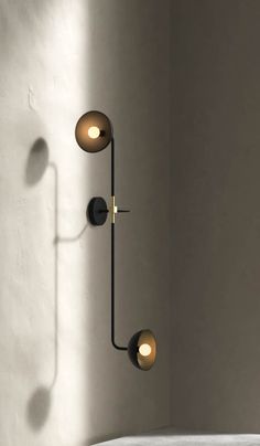 a wall light with three lights on it in a room next to a white wall