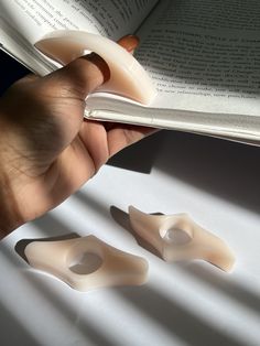 a person is holding an open book and two fake toothbrushes are on the table