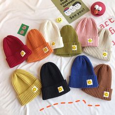 the beanies are all different colors and have smiley faces on them, as well as buttons