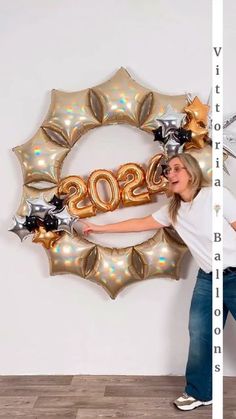 a woman standing in front of a large balloon shaped like a wreath with the number 20 on it