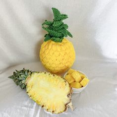 a pineapple next to a bowl of cut up pineapples on a white background