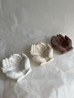 three clay hand molds sitting on top of white paper