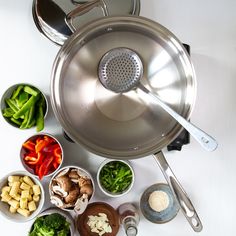 a variety of ingredients are arranged in bowls on a table with a strainer and spatula