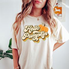 a woman wearing a white shirt with the words hello pumpkin on it and a hat