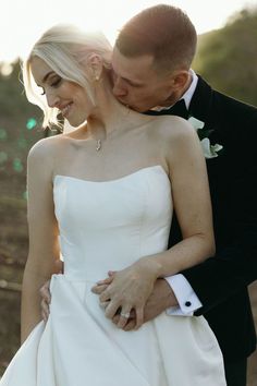 a bride and groom embracing each other outside