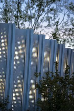 a tall white fence sitting next to a tree