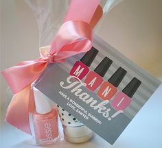 a pink ribbon tied around a gift bag with nail polish and manicures in it