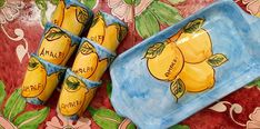 there are four yellow lemons on the plate and two blue plates with names painted on them