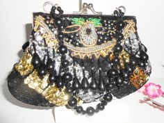 "A glamorous vintage beaded evening bag. Wow, this bag sparkles! The background is black taffeta and it is covered with black, silver and gold sequins and beads. The bag has a silvertone frame and a kiss lock. The interior of the bag is black taffeta and it contains one small pocket. This bag is versatile as it has both a short bead handle plus a chain strap to wear on you shoulder or cross body. This is such a glamorous evening bag. MATERIAL: Beads, sequins, taffeta CONDITION: It is in very goo Black Sequined Party Shoulder Bag, Black Sequin Clutch Bag, Black Evening Bags With Sequins, Black Embellished Pouch Evening Bag, Black Sequined Evening Clutch Bag, Black Sequin Evening Bag For Events, Holiday Handbag, Purple Clutch, Beaded Clutch Bag