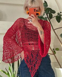 a woman taking a selfie while wearing a red crochet ponchy