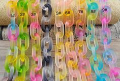 several colors of plastic chain hanging on a wooden table next to twine spools